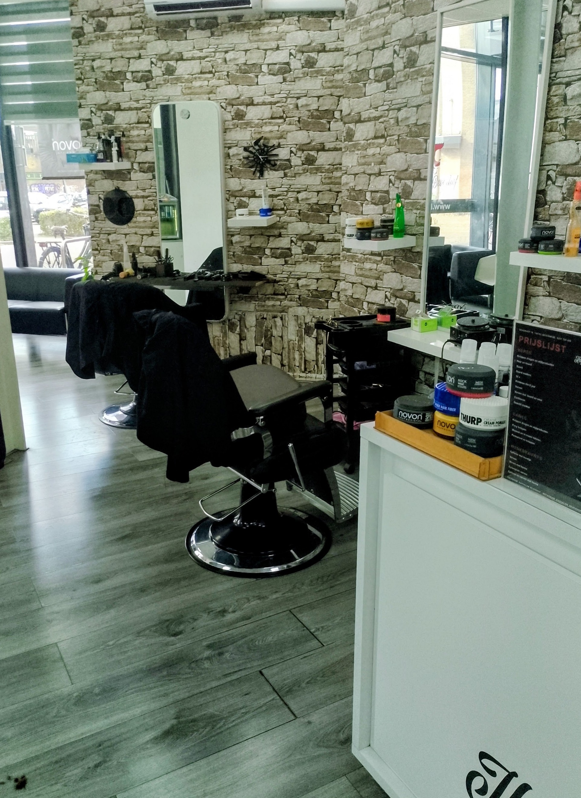 Kappersstoel, grote spiegel en ontvangstbalie in de salon